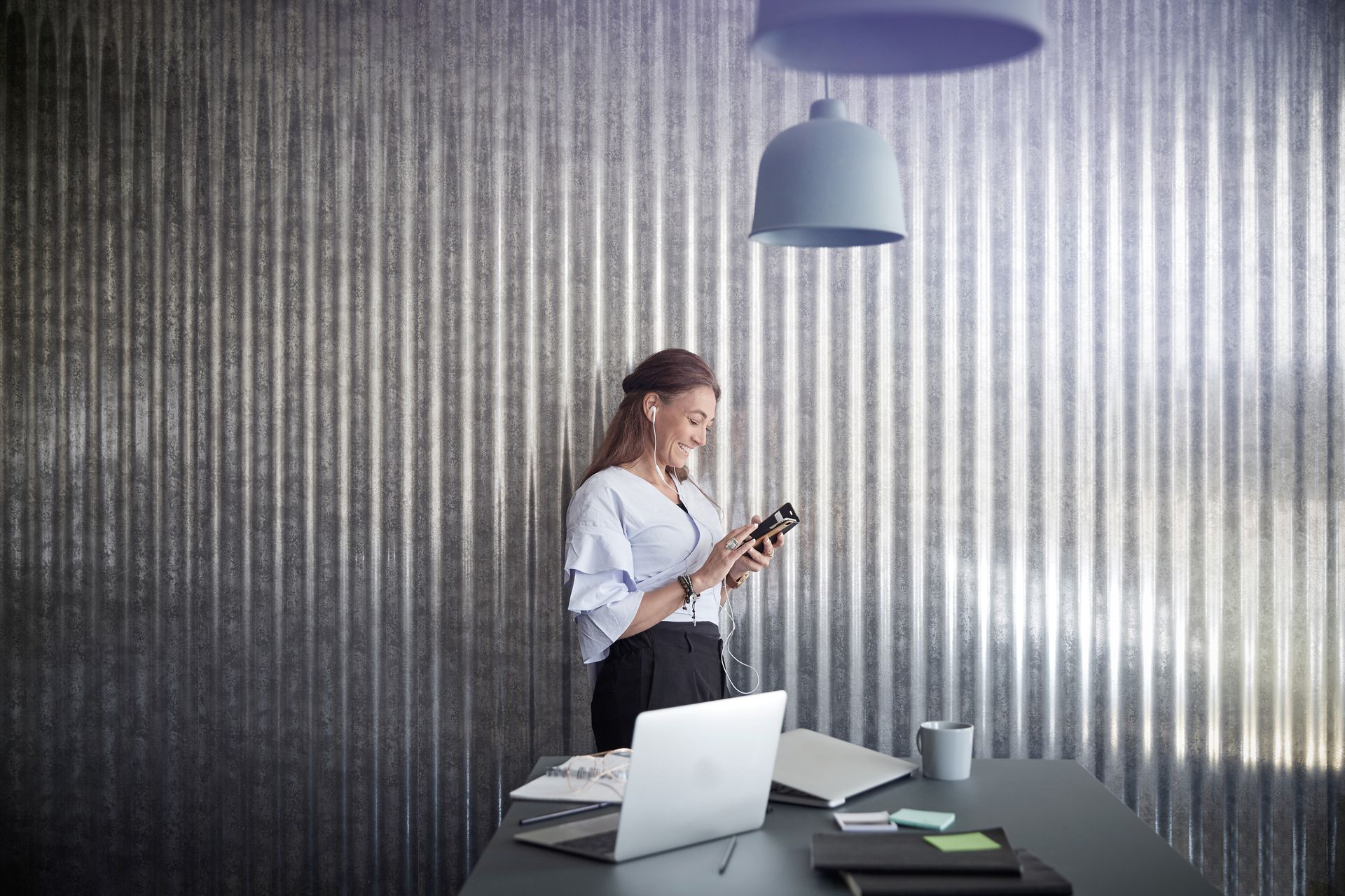 HR-Managerin hinter Schreibtisch schaut auf ihr Handy.