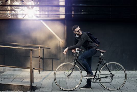 Ein Mann steht lässig auf seinem Fahrrad.