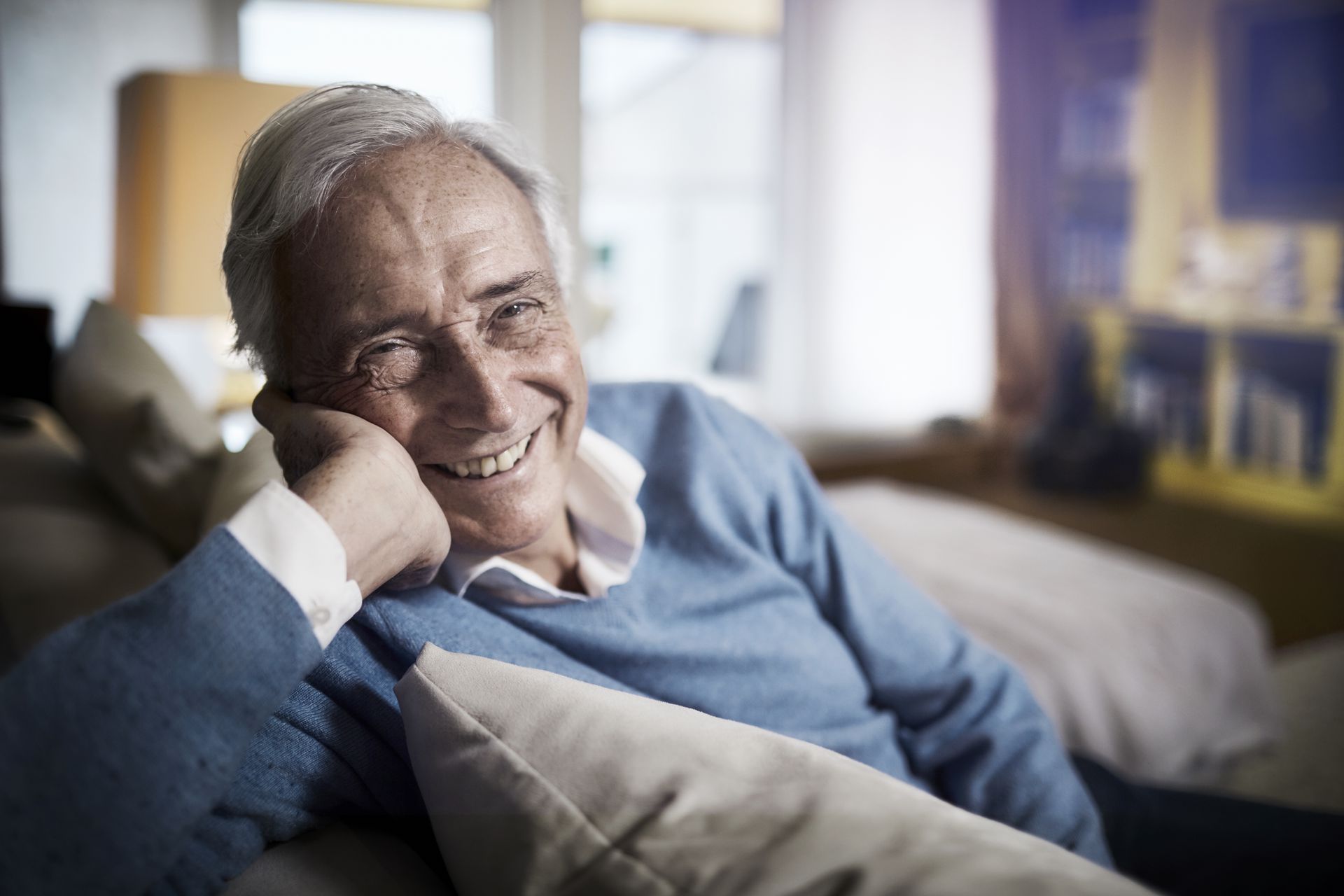 Älterer Mann auf Sofa lächelt unbeschwert