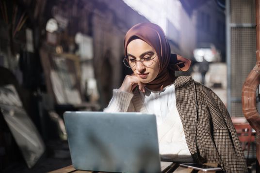 Junge Frau mit Kopfttuch arbeitet am Laptop.