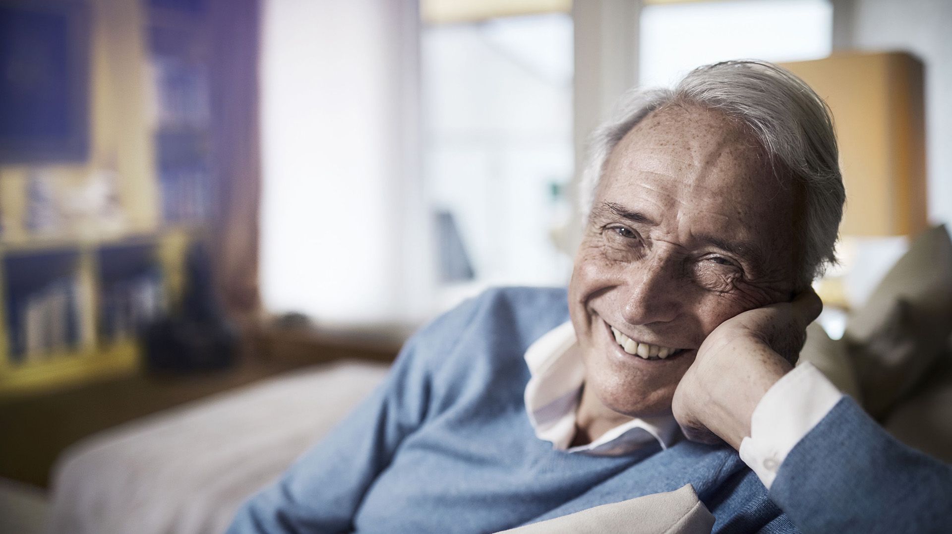 Älterer Mann auf Sofa lächelt unbeschwert