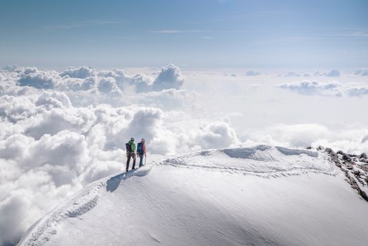 Zwei Wanderer auf einem verschneiten Gipfel.
