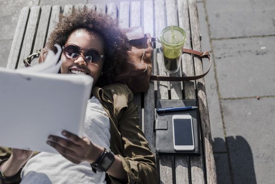 Studentin entspannt lernt auf Parkbank.