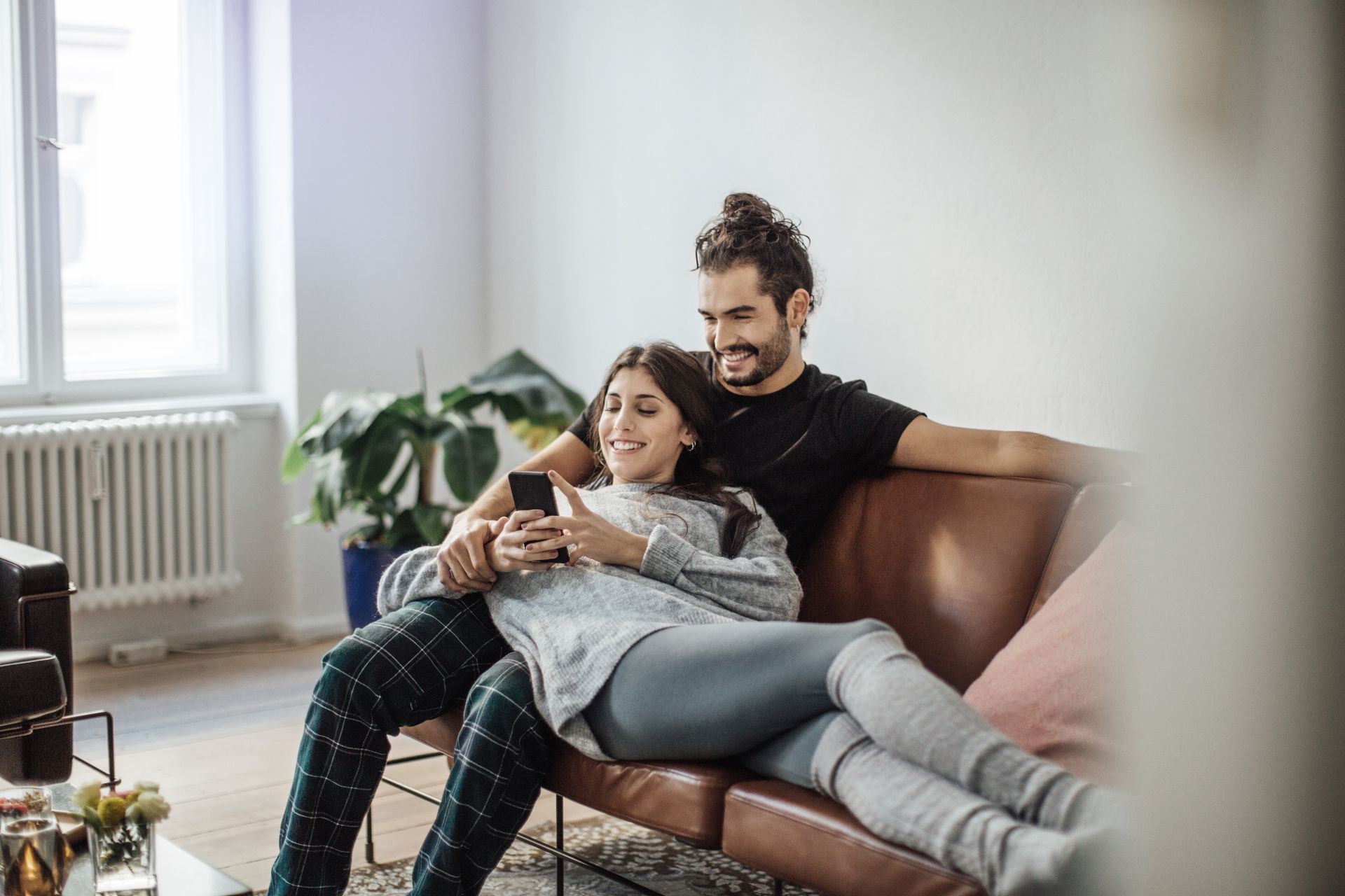 Ein Paar sitzt auf der Couch und schau gemeinsam aufs Handy.